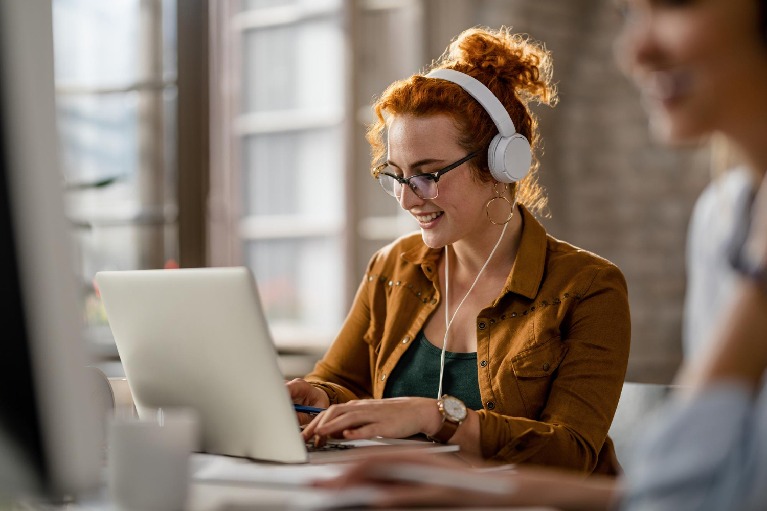 a transcriber sat at a desk listening to audio and transcribing it into words on her laptop
