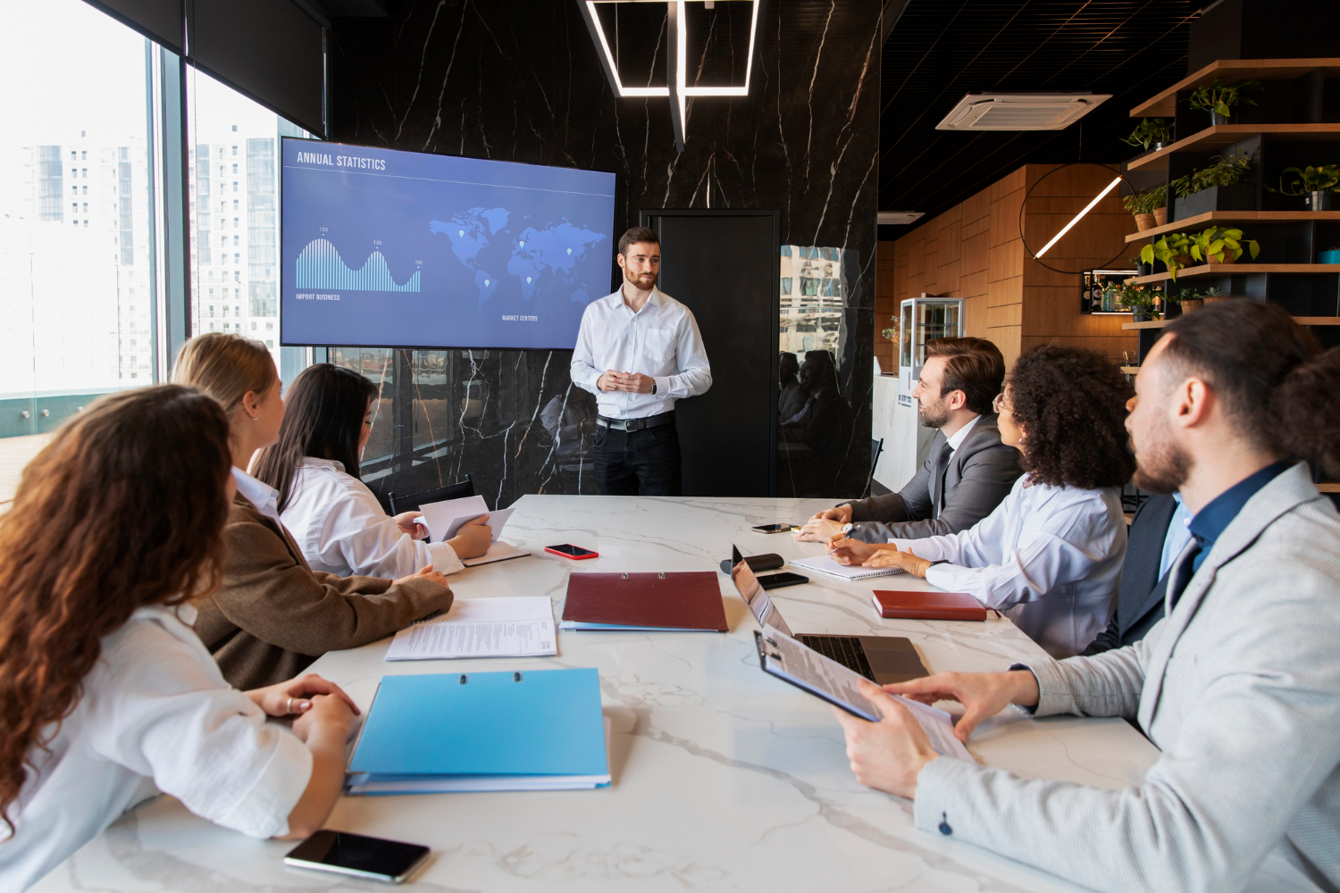 A presentation is being delivered in a boardroom with a data presentation on the screen to audience is investors