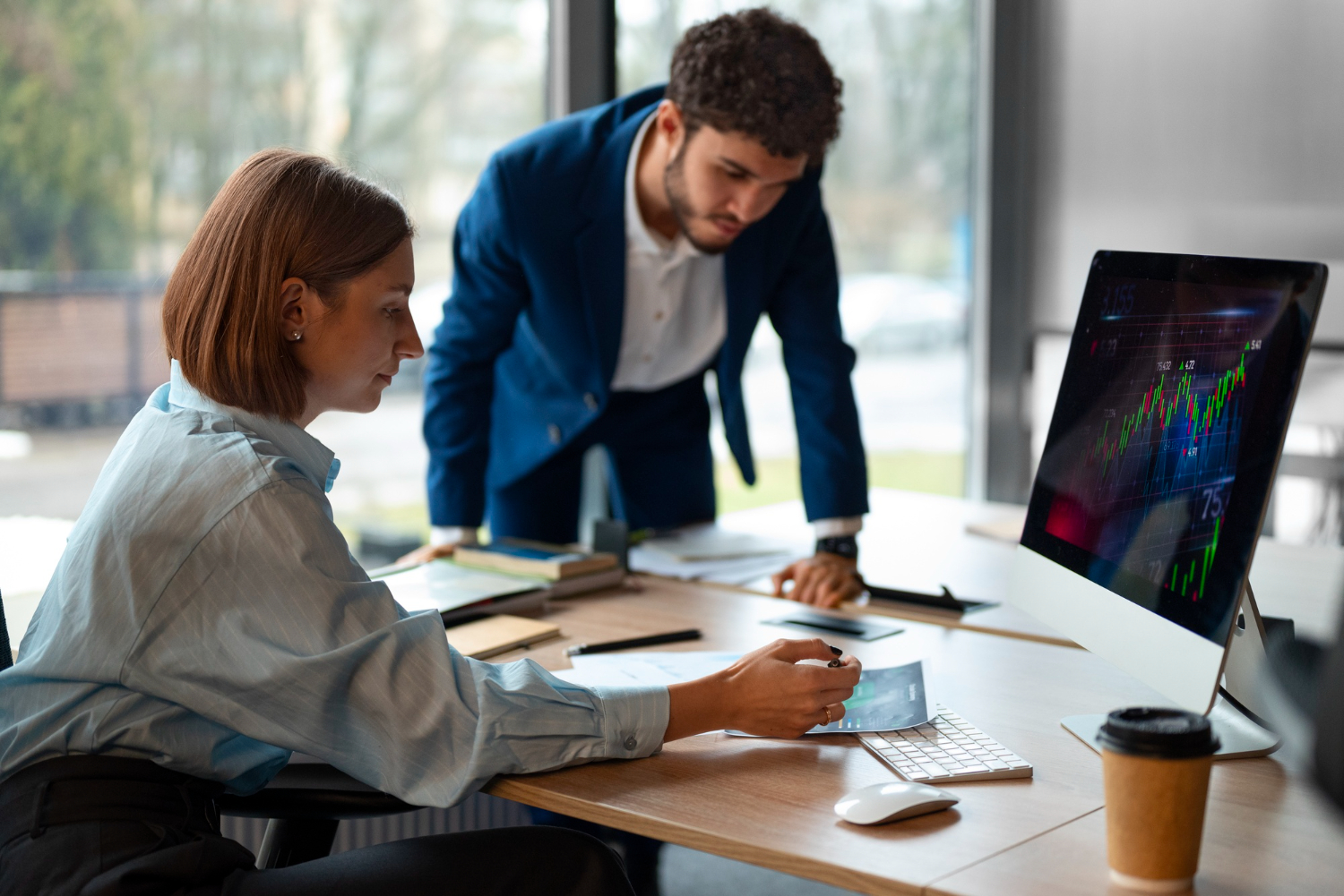 2 people in a bright office reviewing clear translated documents related to stock market guidance