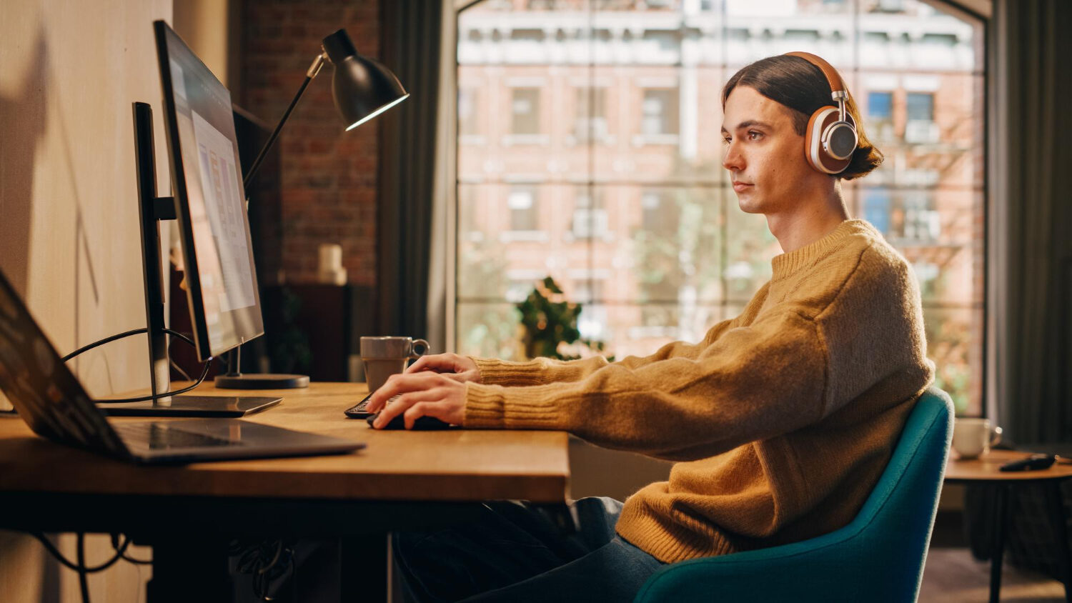 Someone sat at their desk wearing headphones working on a dubbing project