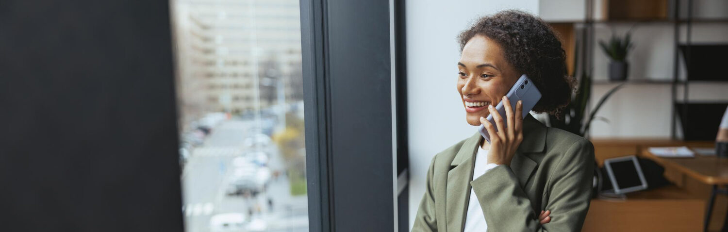 A project manager is on the phone to a client they are smiling after getting good feedback