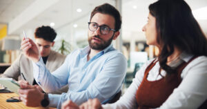 2 colleagues discuss client work at a desk with an Ipad