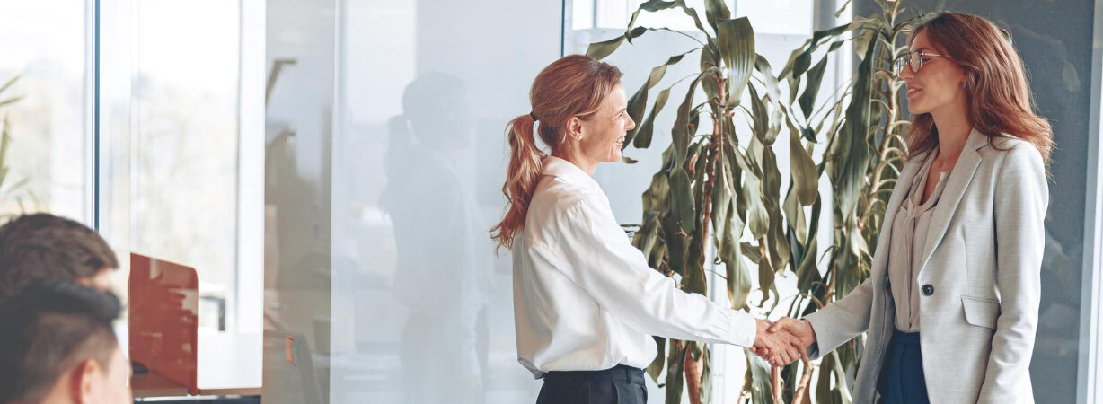 2 people shake hands in a bright office both smiling after a successful job interview