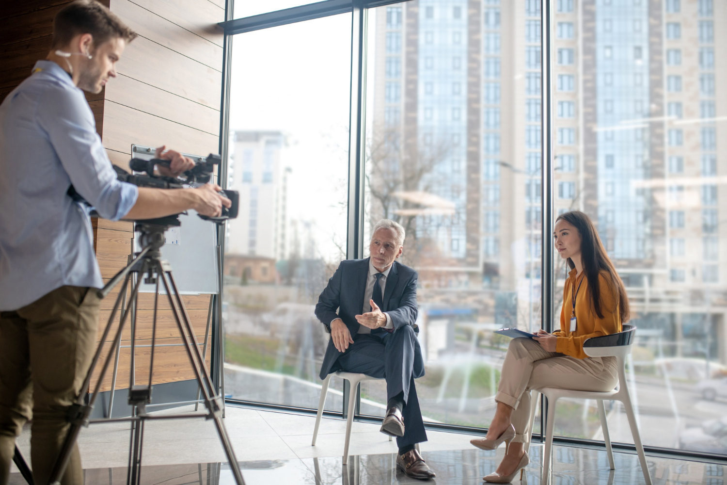 a camera man records a finance professional and an interviewer