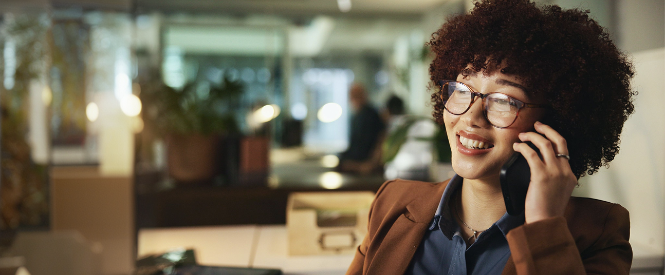 A women working at peter and clark taking a client phone call with a smile on her face