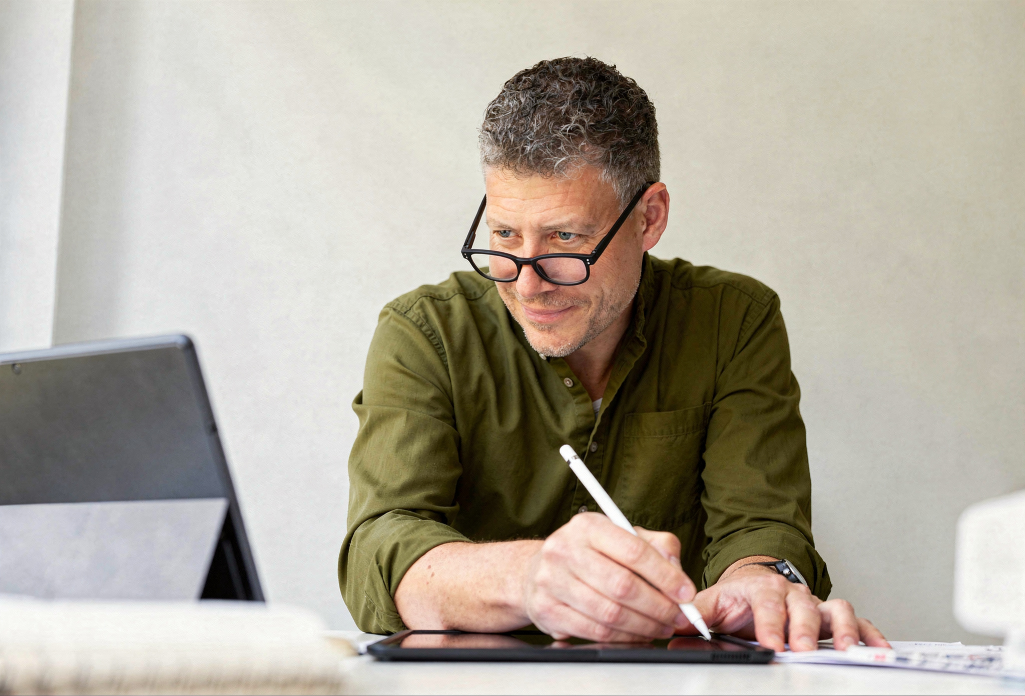 A copywriter sits at there desk taking notes on an ipad, focused on accurately capturing the meaning of the original content