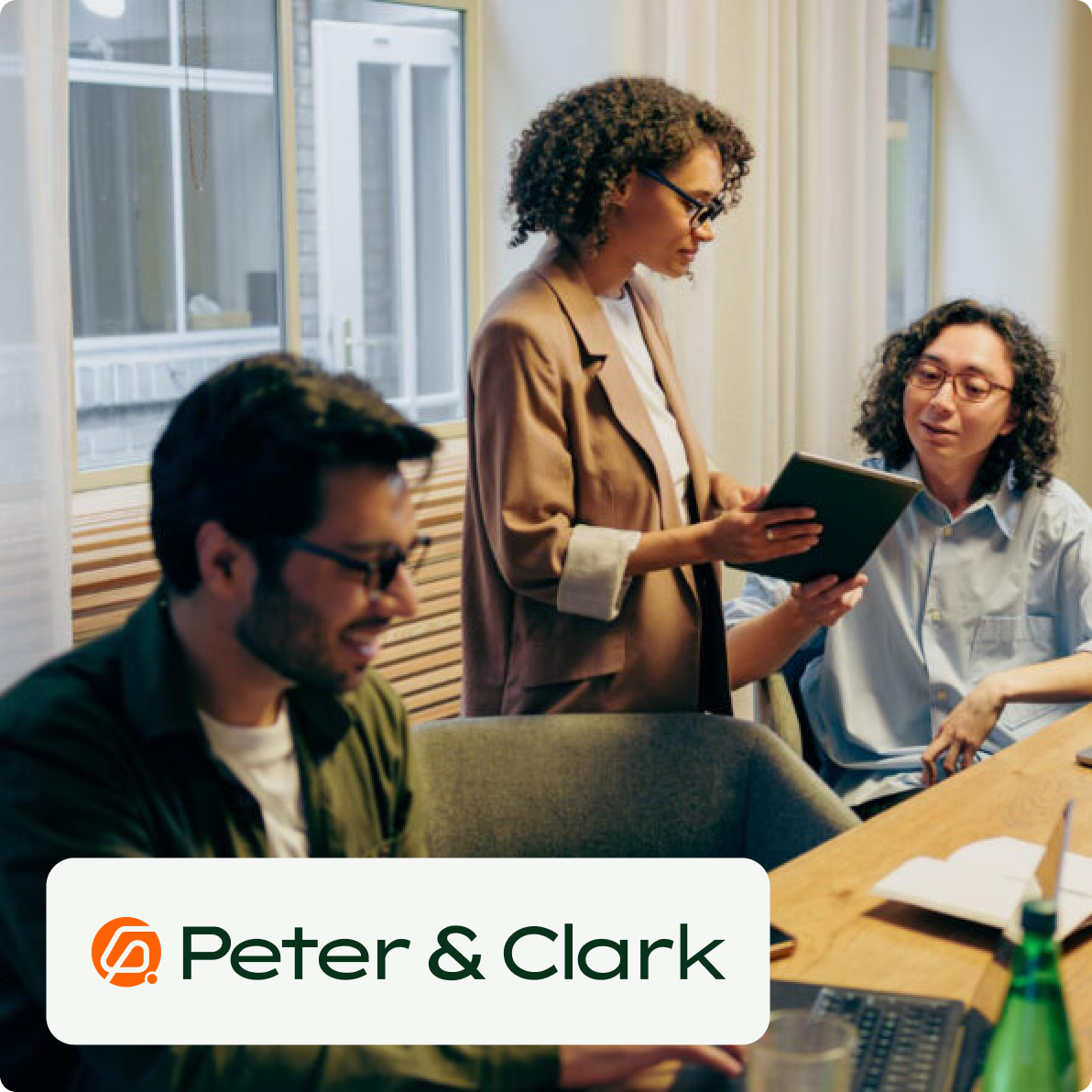 3 people working in an office collaborating with laptops on the table peter and clark logo overlay